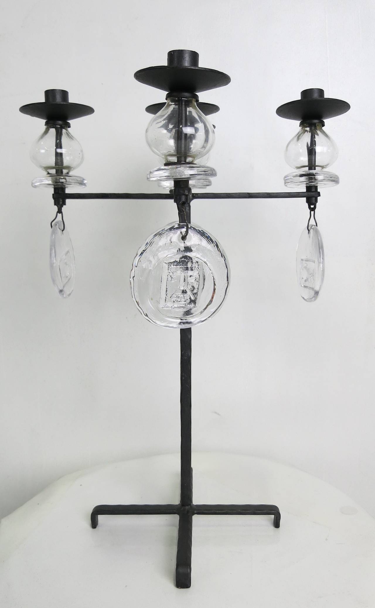 Rare and beautiful form candelabrum by Erik Hoglund for Kosta Boda. The hammered iron frame supports four arms and a central candle cup all raised on poppy form glass bulbs with round glass drops cast with signature Hoglund icons. The piece is in