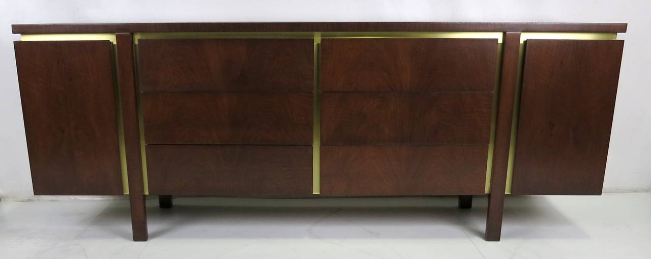 Superb walnut dresser featuring dramatic matched grain drawers with brass trim and parquet top attributed to Bert England for John Widdicomb. The piece has been meticulously refinished in medium-dark walnut lacquer and the brushed brass has been