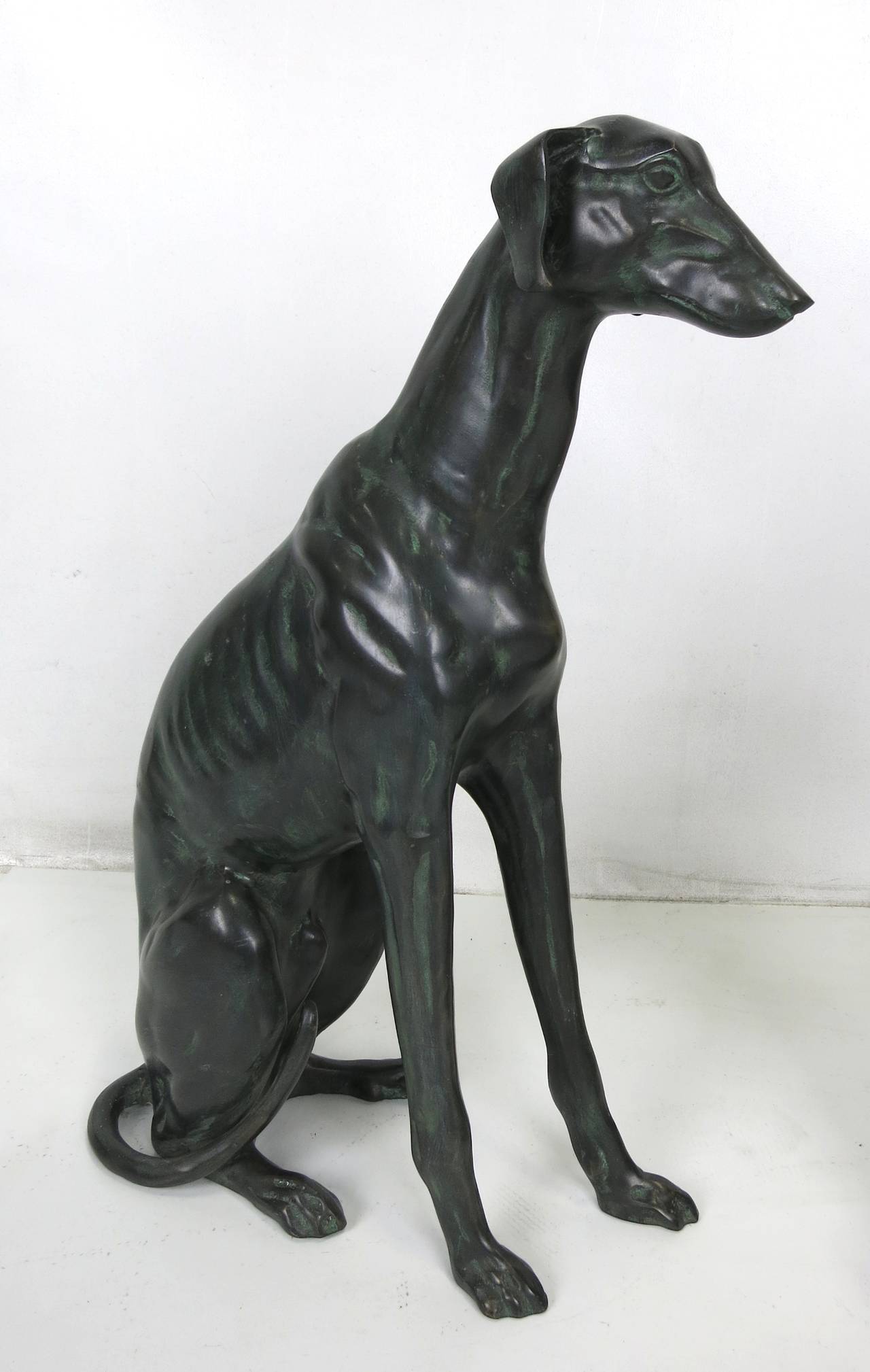 Beautifully rendered pair of patinated bronze whippets, one sitting and one supine. 

Dimensions-
Lying- 25 x 7 x 12 H.
Sitting- 7 x 16 x 23.