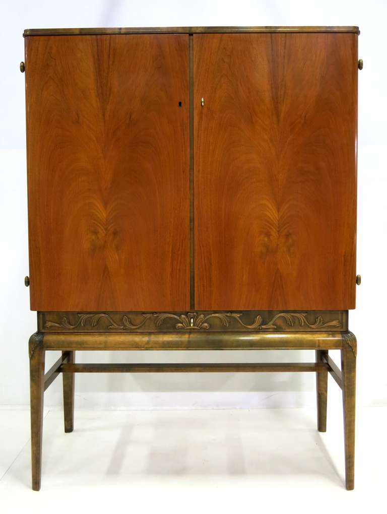 Beautifully crafted Swedish tall Cabinet raised on tapering legs with foliate relief carvings.  There is a locking drawer concealed in the apron and two locking doors.  One side reveals three pullout drawers and an adjustable shelf and the other