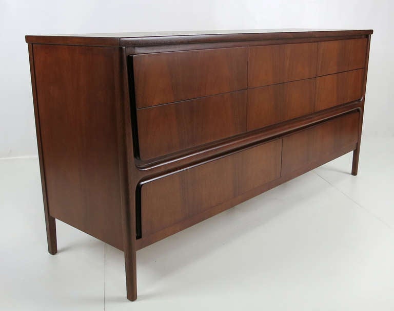 Sculptural walnut dresser with raised legs and vividly grained drawer fronts in the style of Gio Ponti. The drawers and exterior mounted legs stand out in contrast to the recessed cabinet front. The piece has been completely restored in medium