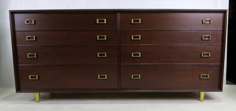 A fantastic example of this classic and highly collectible piece. The eight-drawer chest is accented with two buckle form pulls on each drawer and the cabinet is raised on brass clad solid wood legs. The piece has been freshly refinished in deep