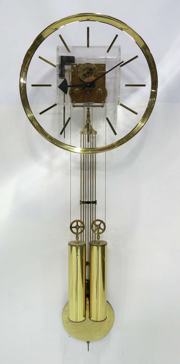 Lucite and Brass Pendulum Wall Clock by Howard Miller.  This is a 7 day wind-up clock with working pendulum and chime.  Features the George Nelson markers and hands.