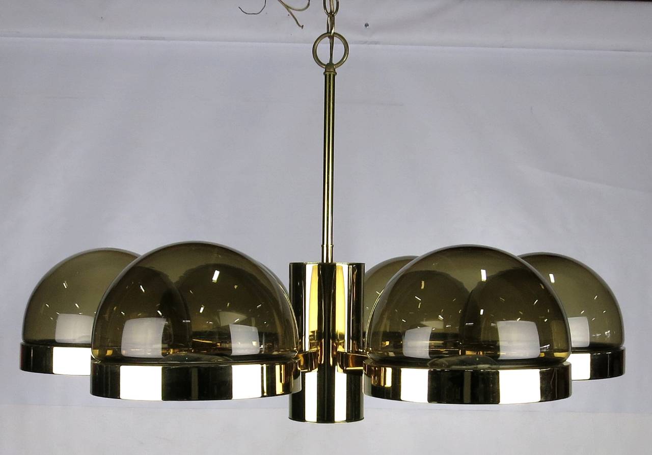 Impressive and large chandelier in brass and smoked glass attributed to Gaetano Sciolari. Featuring six lights surrounding a central hub that houses a recessed downlight. The glass shades can be installed above or below the mounting ring.