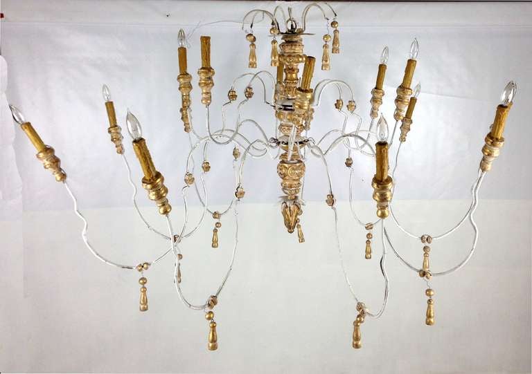 14 arm Gilt wood chandelier with long undulating metal arms with waxed candle sockets and gilt wood tassel ornaments.