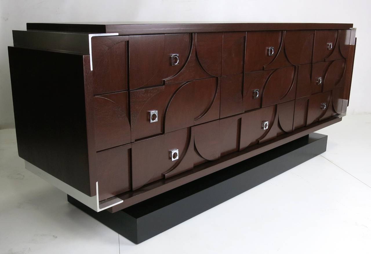 Fantastic walnut dresser with aluminum corners, raised on an ebonized hardwood base heavily influenced by the works of Louise Nevelson and Paul Evans. The piece has been meticulously restored and refinished to mint condition.

Paul