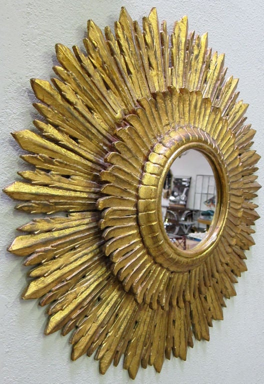 Dramatic hand carved gilt wood Sunburst Mirror with three layers of carved stylized rays.