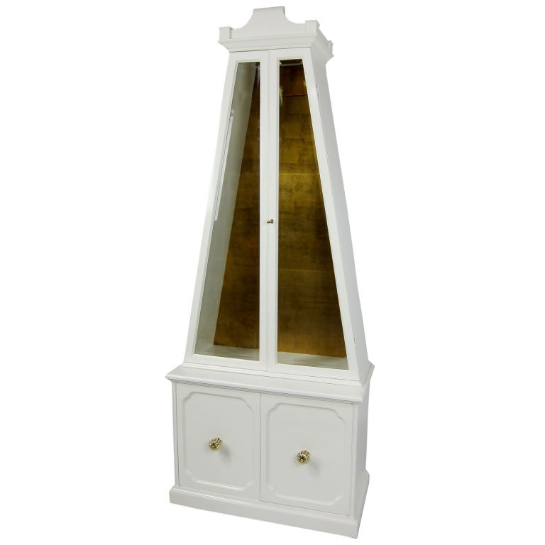 Spectacular large Obelisk form vitrine or bookcase. The upper showcase portion features a fine hand-done gold leaf back wall and two glass shelves along with beveled glass doors. The bottom cabinet has large, solid brass door hardware and one
