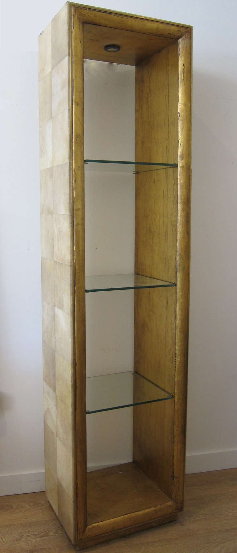 Pair of tall parchment wrapped display shelving with three glass shelves.  Gold leafed interior finish, recessed light.  

This item is located in Manhattan at 1stdibs@NYDC showroom.  200 Lexington Ave.  10th Floor, NYC.