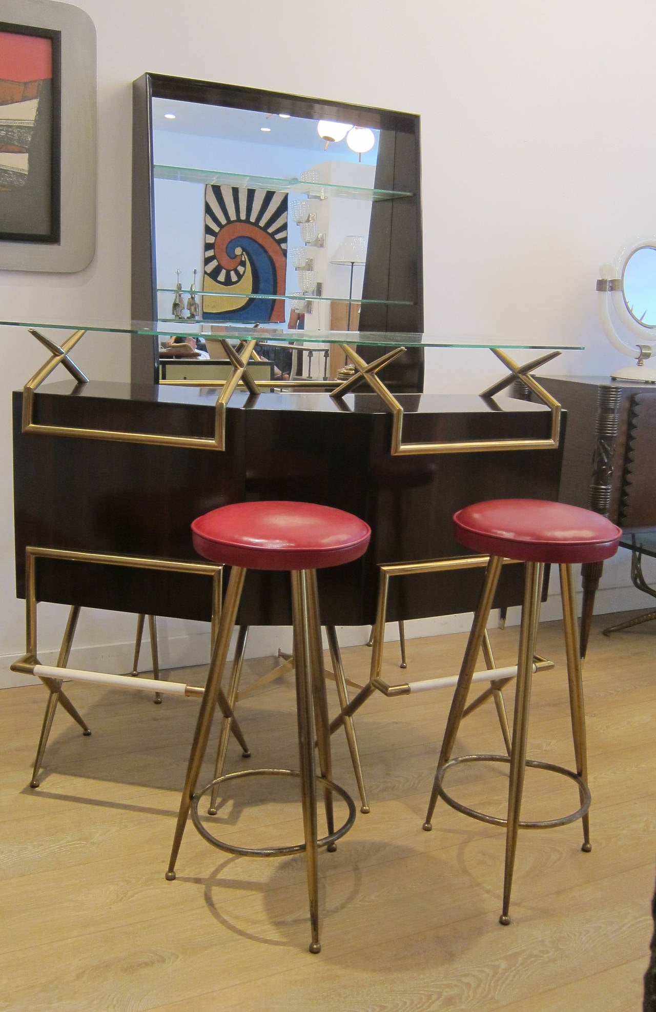 An exceptional rosewood and brass 1950's Italian bar suite comprised of a dry bar, two brass stools and a bar back/vitrine.
Wood work restored to perfection all brass work left in original condition with nice patina. Newly upholstered leather