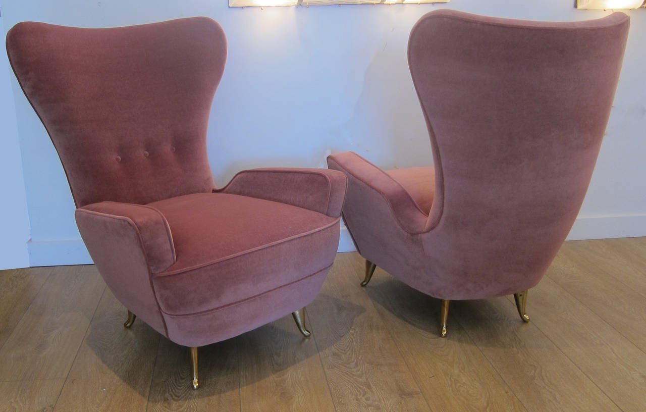 Pair of curvaceous Italian lounge chairs, circa 1950. Newly upholstered with mauve velvet, brass legs.
