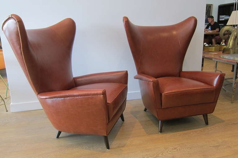 Pair of 1950's Italian tall wing back armchairs, newly upholstered in tobacco leather, ebonised conical wood legs.

.