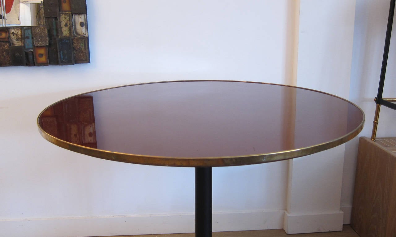 Italian gueridon/center table, brass and black metal base. Burgundy piano finish top, inset in a brass trim. Brass is in original condition to preserve vintage patina.