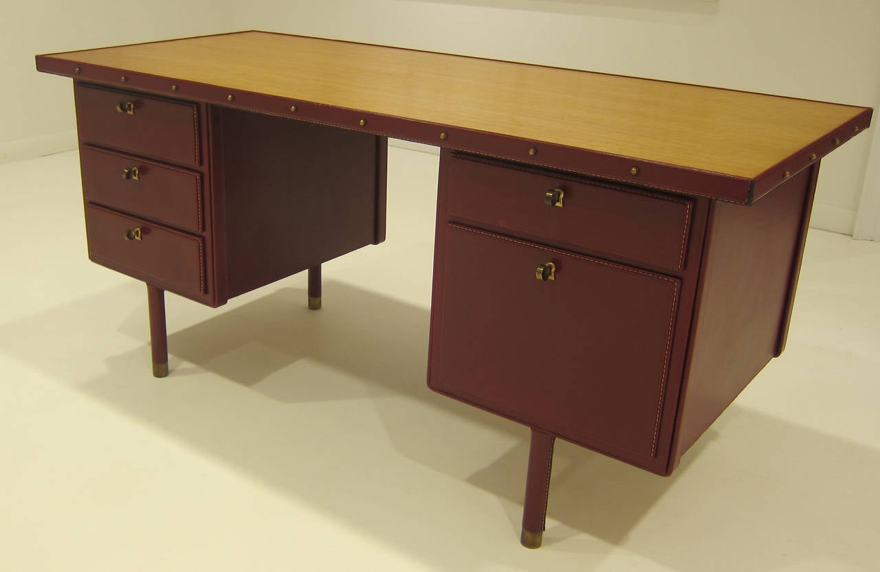 Rare double pedestal desk by Jacques Adnet. Red stitched leather wrapped,  oak top, brass fittings, with all original keys.