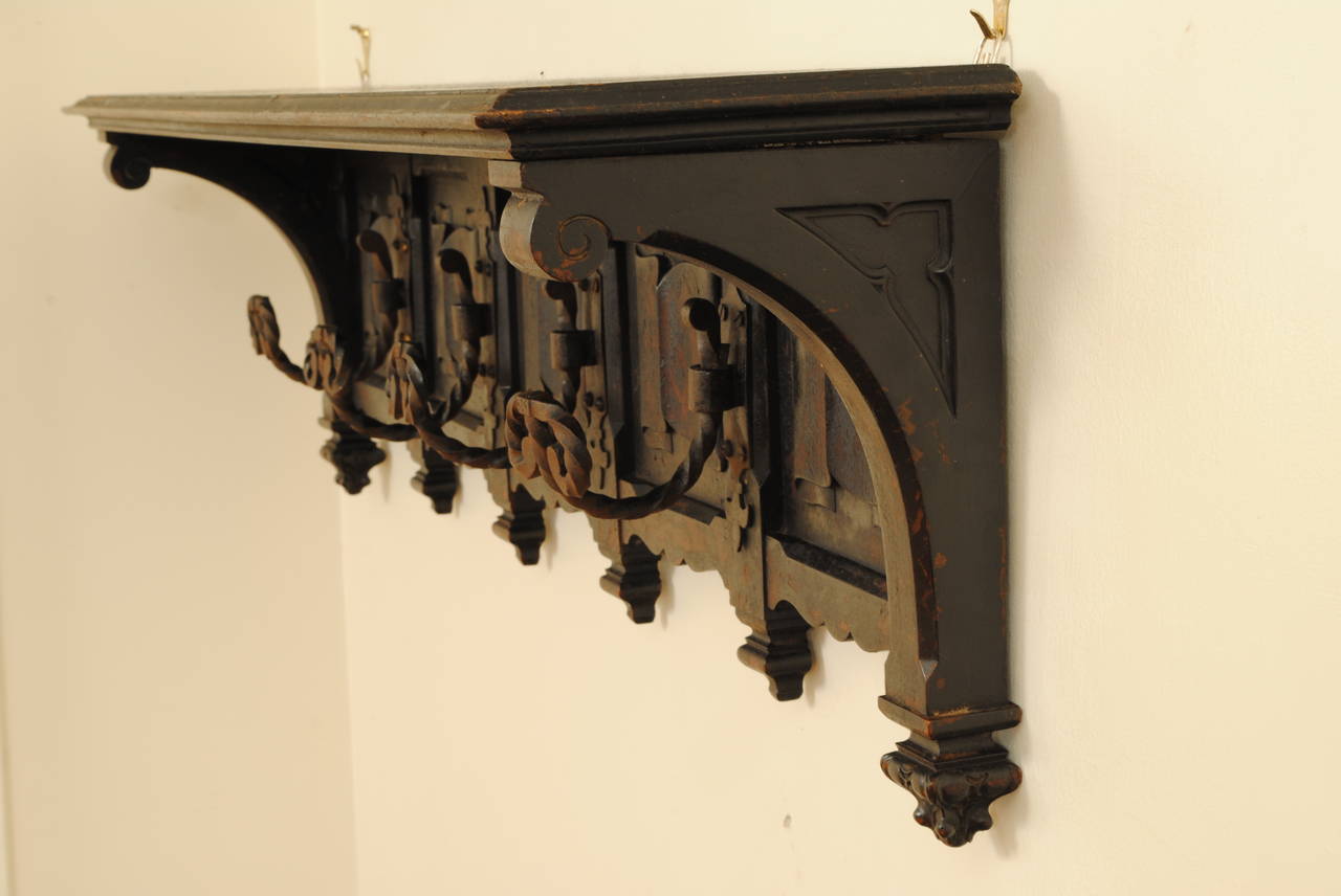 Having a shelf top supported by two carved arch brackets, the back with linen-fold carvings and spiral turned wrought iron hanging hooks, below each hook and brackets are carved corbels.
