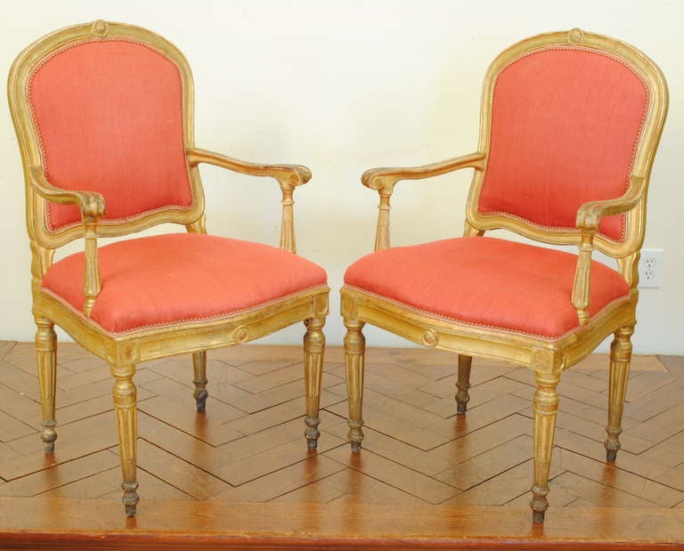 the arched backrests with a centered medallion, the carved arms and carved handles on fluted supports, generously proportioned upholstered seats above shaped aprons with repeating centered medallions, raised on tapering fluted legs and raised ball