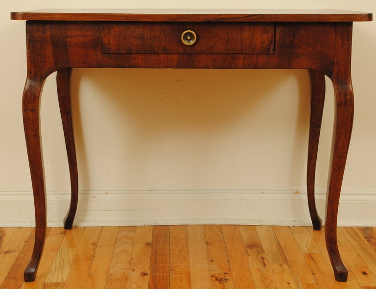 probably Tuscan and having a rounded edge rectangular top covered in a lozenge pattern, the solid walnut base housing one drawer with a brass pull and having flared tapering legs and small raised feet