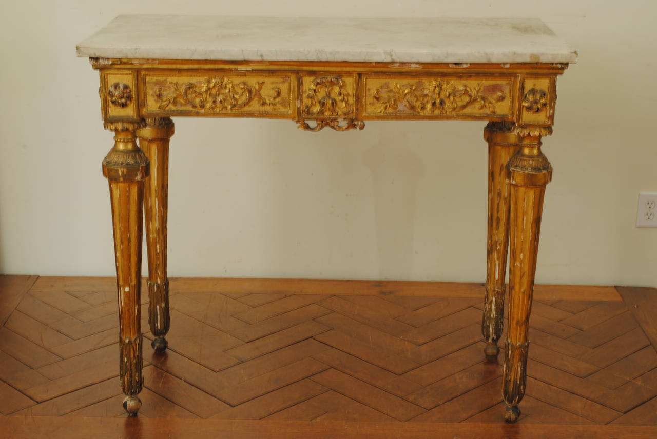 The rectangular marble-top above a conforming giltwood console table with precise carvings and tapering fluted legs, raised on small ball feet.