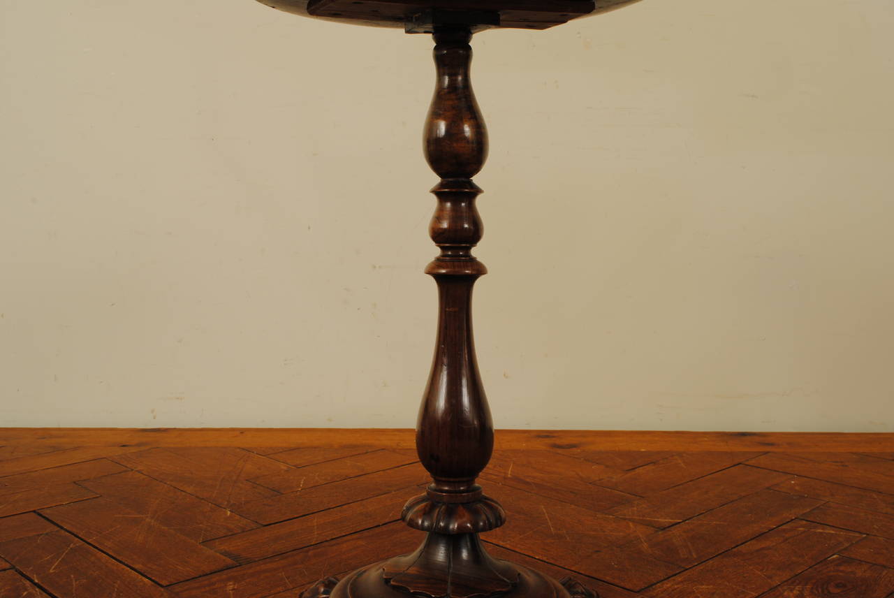 the circular top with a raised and carved edge above a vase turned support resting on a round plinth base atop carved paw feet