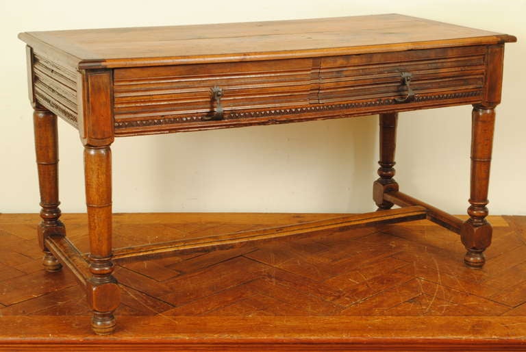 the rectangular top above a conforming case housing two drawers with molded and carved panels, the decorative details continuing to the sides and rear of the table, raised on turned and tapering legs joined by an h-form stretcher, raised on ball