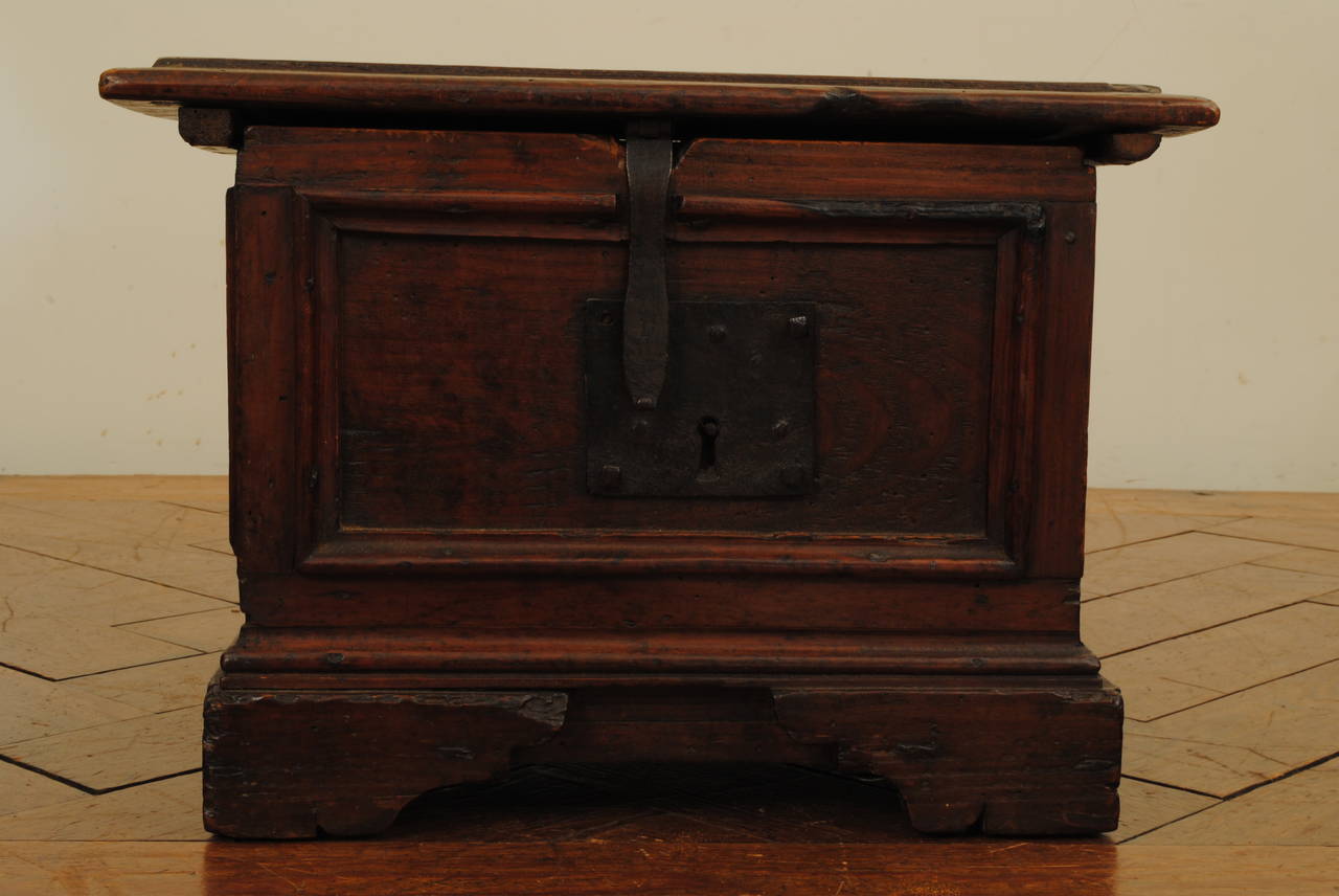 Having a rectangular top with a molded edge above a conforming case with paneled sides and resting on straight sides and front bracket feet, the iron lock on the exterior.