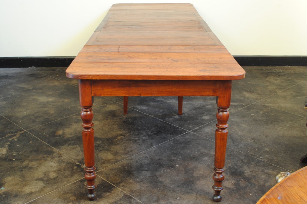 the rectangular rounded edge top above a conforming apron resting on well turned legs and raised on wall feet, the table with original mechanisms and locks for securing it without leaves, when leaves are added the middle legs unlock and fold down in