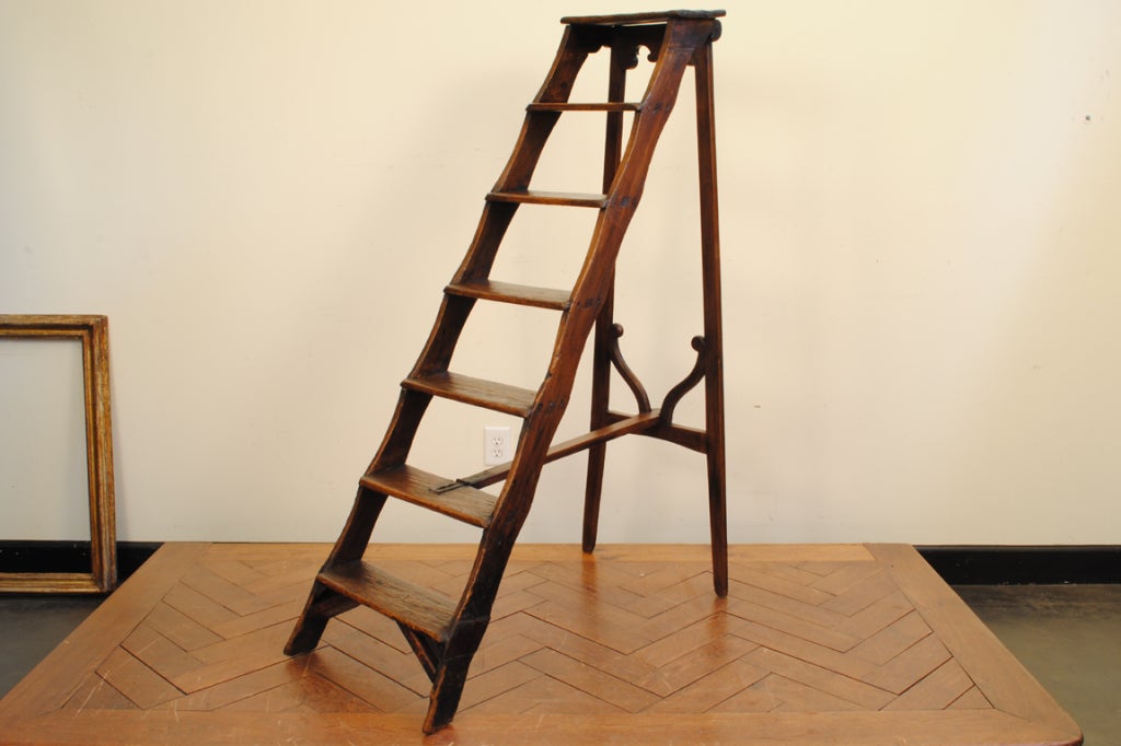 the folding ladder constructed of pine with iron hardware, decorative carving at base