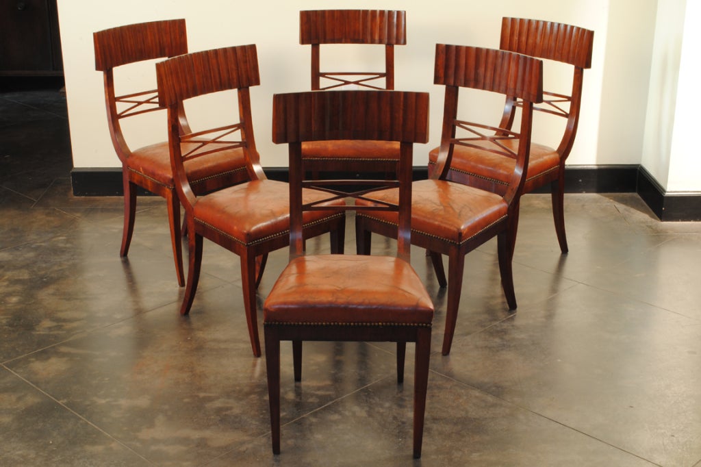 the set of six chairs having fluted concave backrests with decorative x-form stretchers above leather upholstered seats trimmed in nailheads, resting on flared and tapering legs

Please go to www.robuck.co to see our complete inventory.