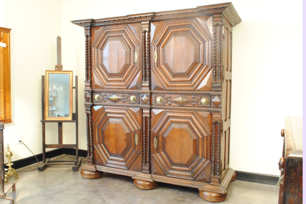 The case having four doors and three drawers with brass escutcheons and pulls, with original locks, the sections separated by double sets of turned columns, the carved door panels of octagonal form and having four concentric sections, resting on