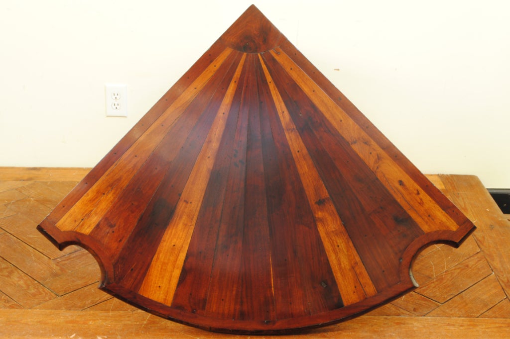 having a slice of pie shaped top with alternating bands of thick mahogany and fruitwood veneers, the front of the top with opposite concave sections above solid fruitwood columns continuing to a concave shaped triangular base raised on elongated