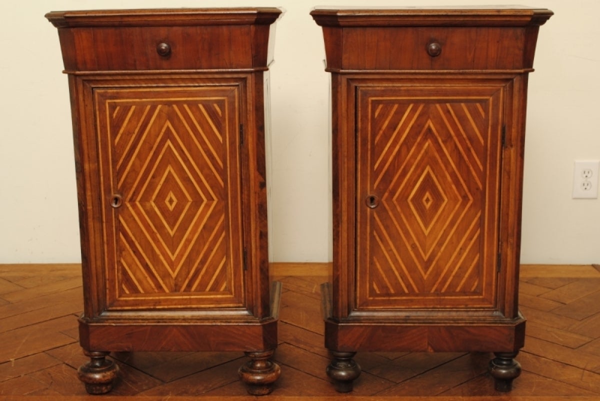 Beautifully inlaid with lozenge patterns, the tops with centered starbursts, having drawers over locking doors, raised on turned bun feet

