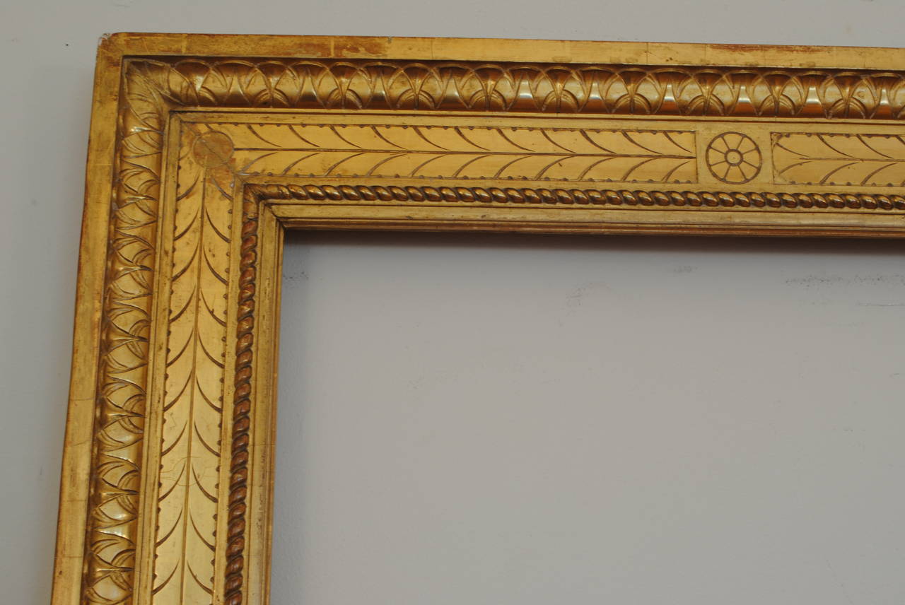 Retaining its original beveled mirror plate, the rectangular frame carved and beautifully water gilded in 23-karat gold leaf, the sides having an interesting paneled detail.