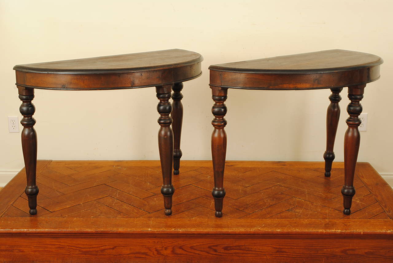 constructed entirely of solid walnut, the half-round walnut tops having molded and ebonized edges, the aprons with lower ebonized edges, raised on turned legs with alternating walnut and ebonized sections