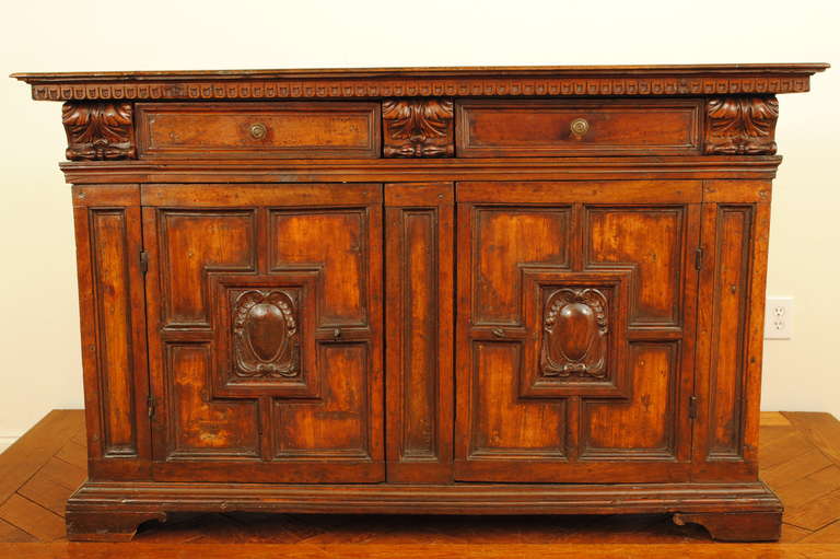 the rectangular top with dentile molded edge above a conforming case housing two drawers between robust corbelle carvings, the two paneled doors having carved stemmas, raised on a plinth-form base atop bracket feet

Please go to www.robuck.co to