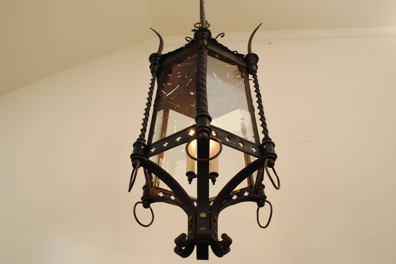 the curved conic metal top with decorative scrolls and six curved spikes above a frame consisting of scrolled iron supports and having six glass panes, the bottom of the frame decorated with pierced quatrefoils, the bottom with round loops