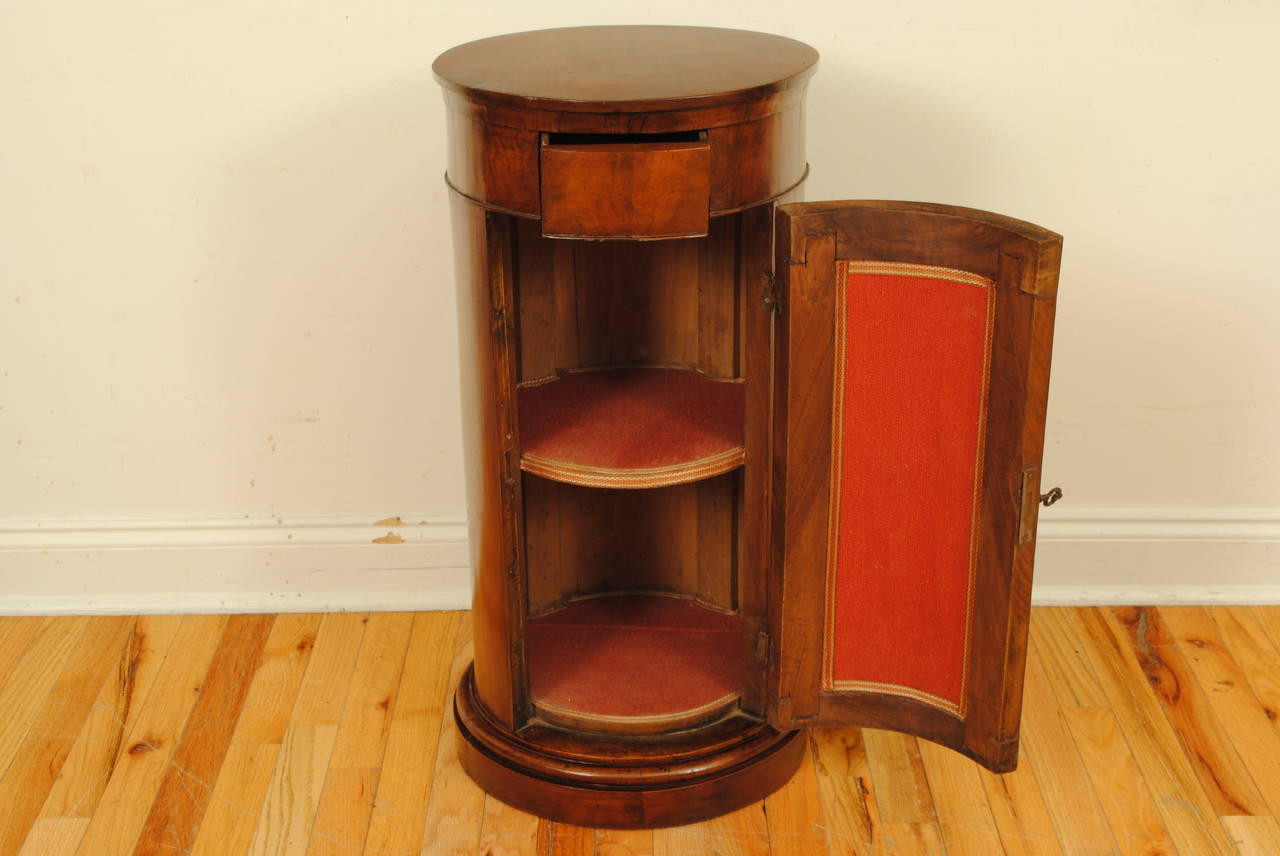 Circular top above a conforming case with one drawer and a locking door on plinth base, diameter of base is 15 inches.