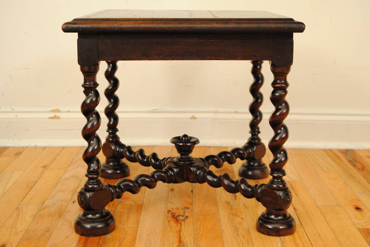 having a square top with molded edge on turned legs joined by an x-form stretcher with turned finial