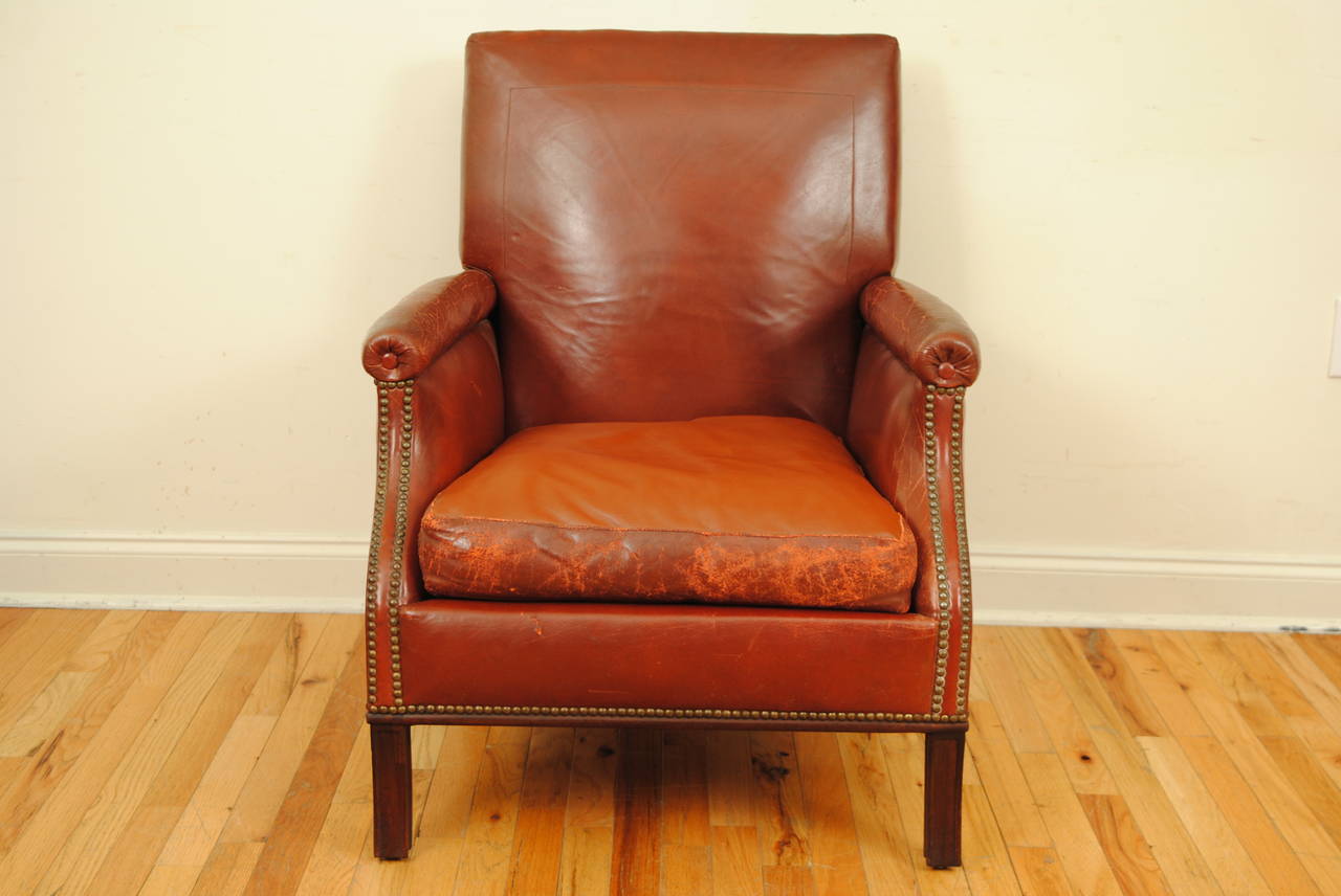 The reclining rectangular back connected to the arms by brass and steel ratchets, with loose cushion, trimmed in nailheads, raised on flared tapering legs.