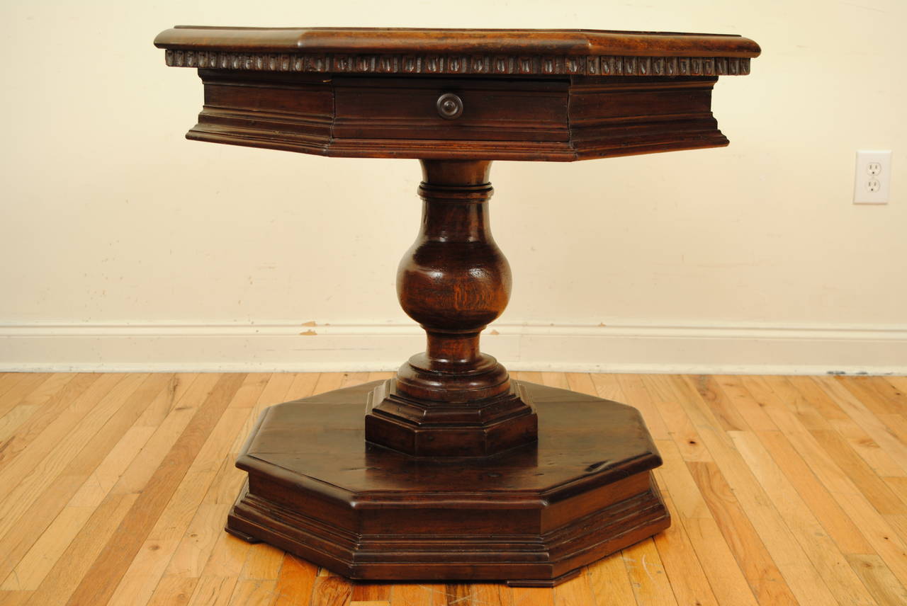 The octagonal top having a molded edge above a conforming case housing one drawer, supported by a thick turned pedestal atop an octagonal plinth base.