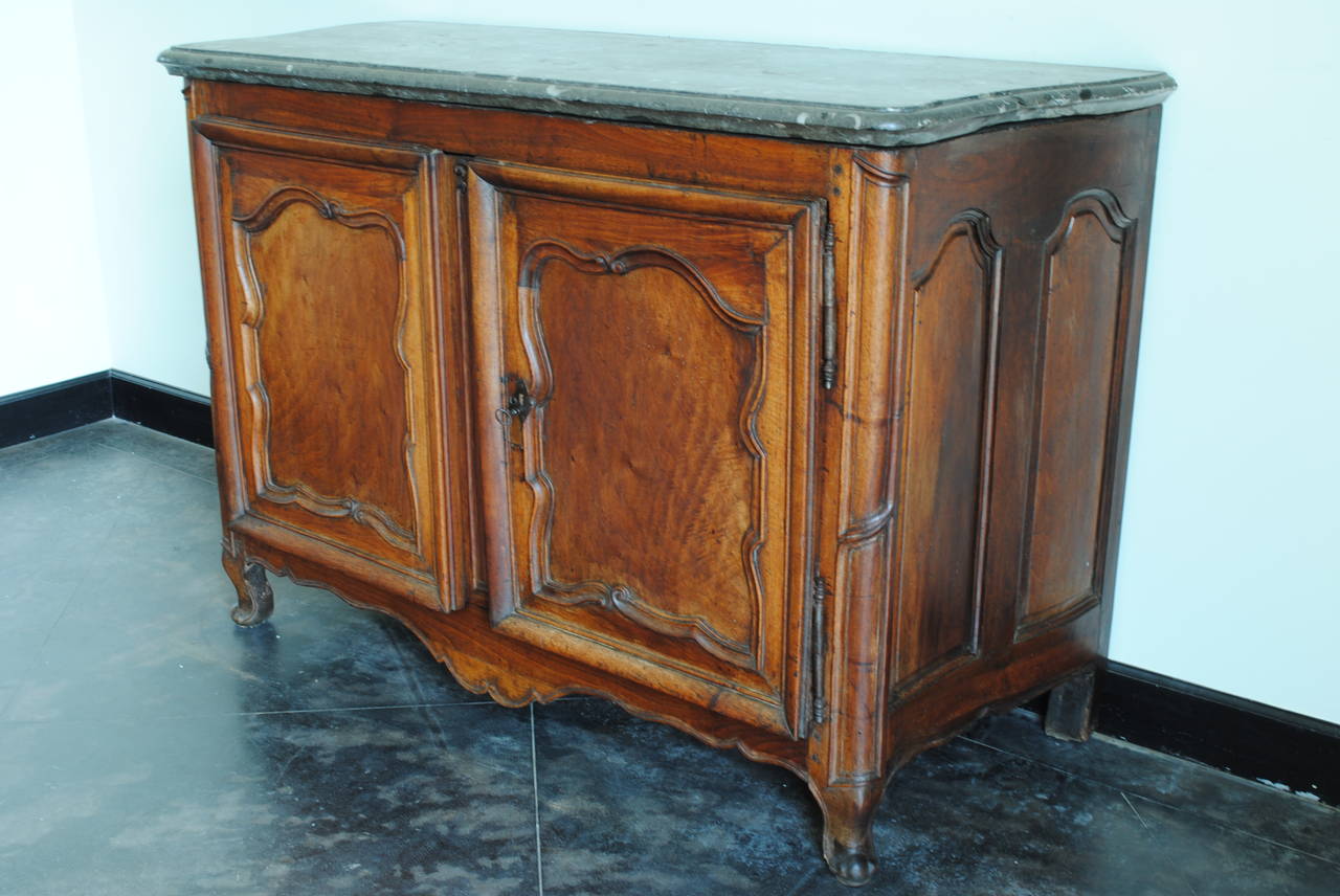 Rare Louis XIV/XV period carved walnut buffet, Marrone fossilized marble top having a thick shaped Maronne Fossil marble top atop a conforming case with stylized carved door panels and rounded corners with carved feet and apron, the interior and