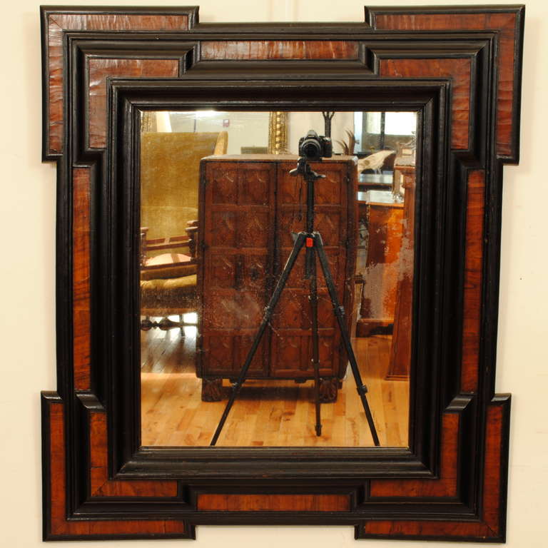 having stepped corners and multiple layers, walnut veneers within ebonized moldings, retaining antique mirrorplate. Possibly Italian