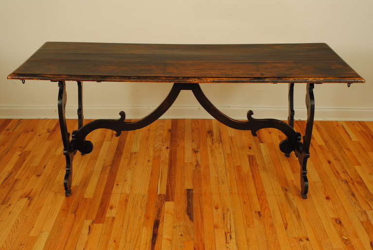 Rectangular three board top with molded edge atop shaped trestle supports connected by a shaped stretcher, having iron pull out supports with rings for use (previously) with leaves. 18th century with later alterations.