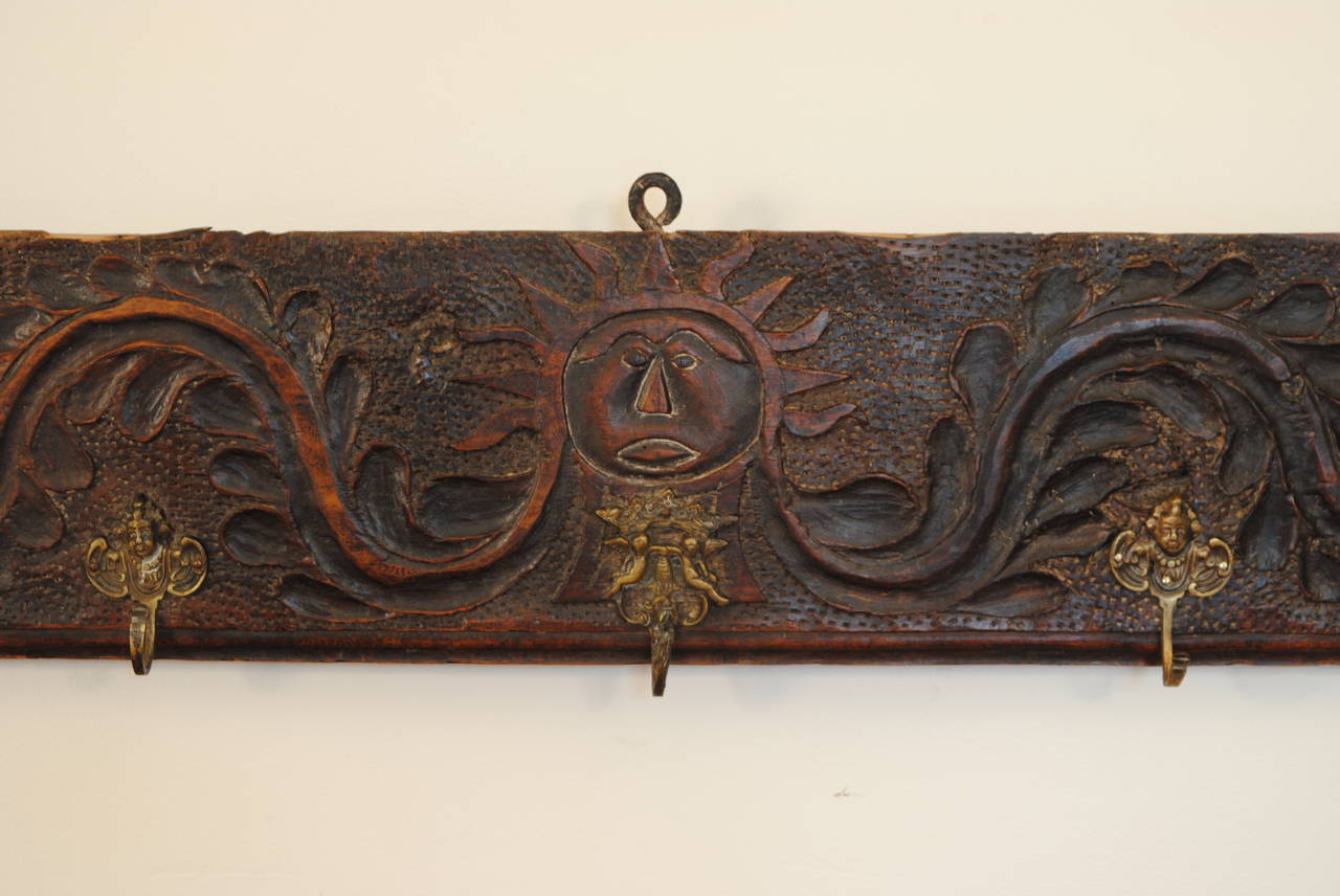 Having a carved scroll with a center figural sunburst