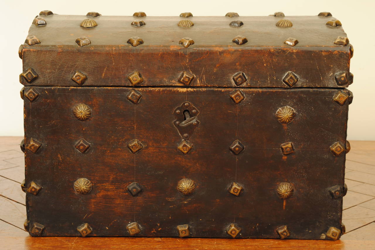 Early 18th century leather upholstered carrying trunk. The interior revealing an open well and separate raised storage area, having iron hinges and an iron antique lock.