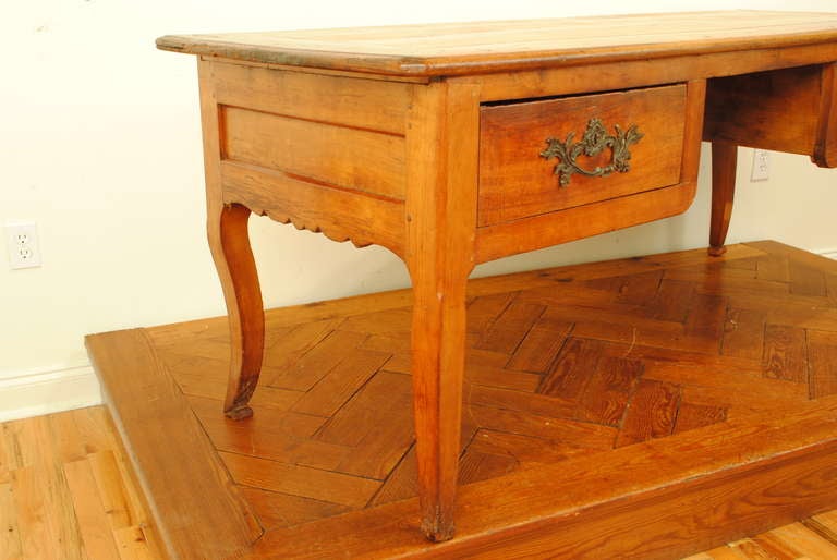 having a rectangular top with slightly rounded corners and a slightly beveled edge above a conforming case consisting of paneled sides and back with carved aprons, the two large drawers surmounted with period patinated brass hardware, the curved