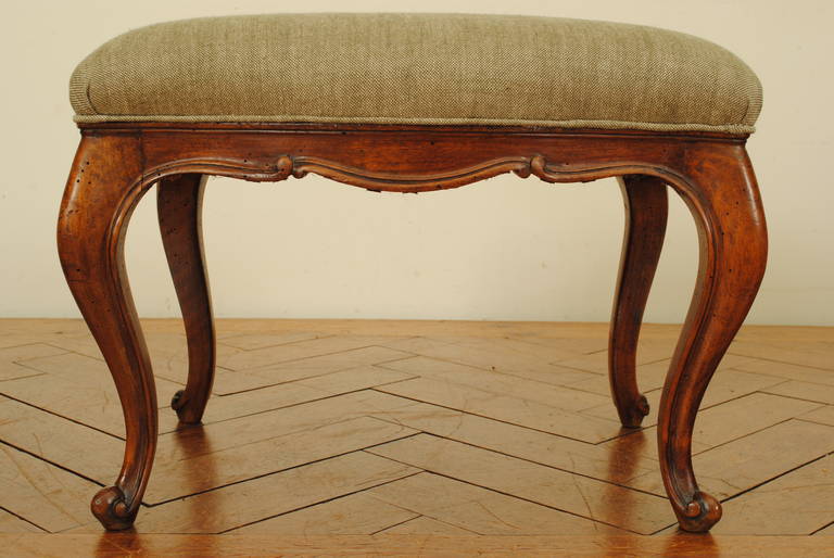 of rectangular form, the upholstered seat above a carved apron and raised on carved cabriole legs