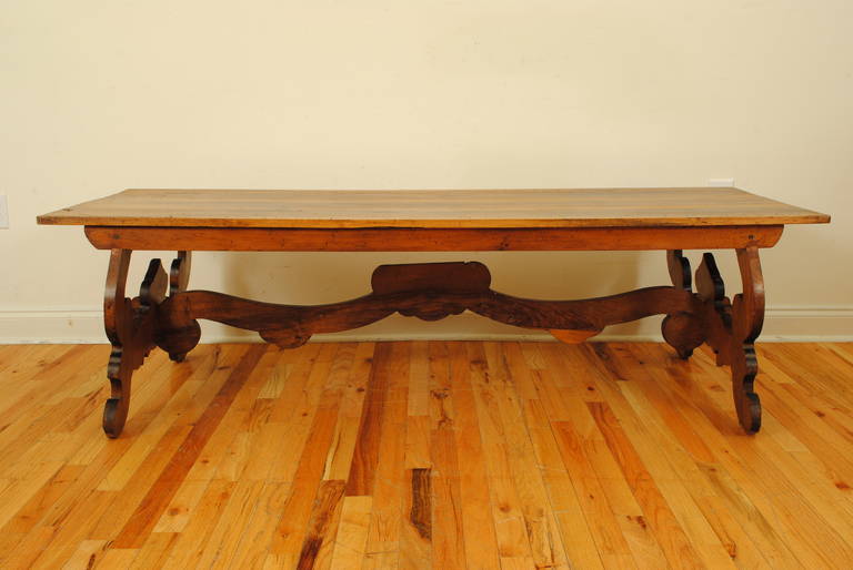 The rectangular top consisting of three boards atop a small apron and supported by a pair of lyre-form trestles connected by a shaped central stretcher, reduced in height to make a coffee table, the width measured to the outside of the feet which