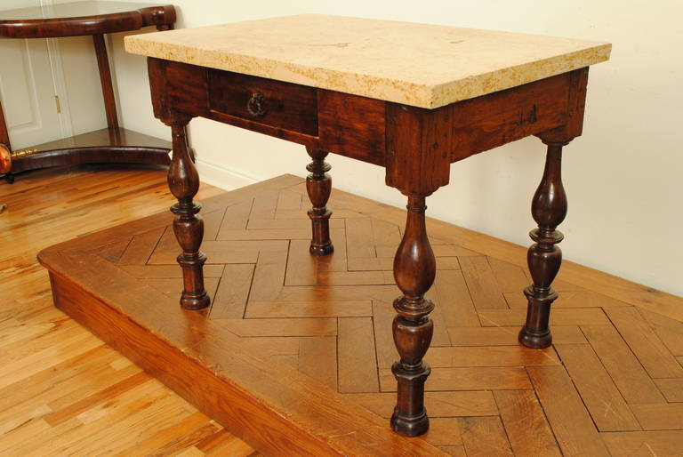 Having a massive marble top above a case housing one drawer with a wrought iron pull, raised on wonderfully turned legs