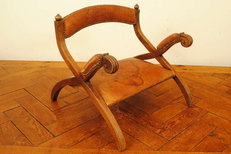 of inverted curule form and having raised arms and an arched backrest, upholstered in original leather, used as a low chair and a prayer bench

Please go to www.robuck.co to see our complete inventory.