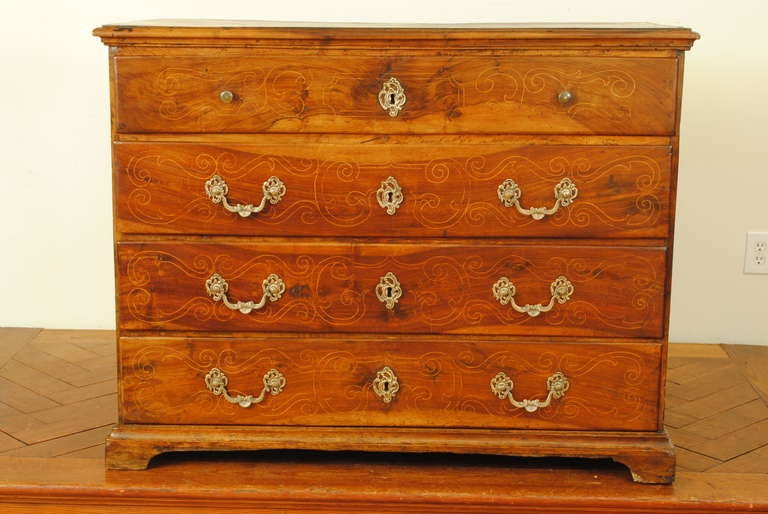 Of Swiss or far Northern Italian origin and having a rectangular top with an applied moulded edge above a conforming case housing four drawers with bronze, probably original, hardware, the doors and sides detailed with a patterned inlay evoking the